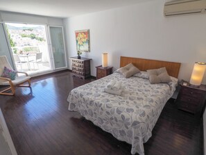 Une chambre à coucher avec un lit, une chaise, une commode, une lampe et un tableau.