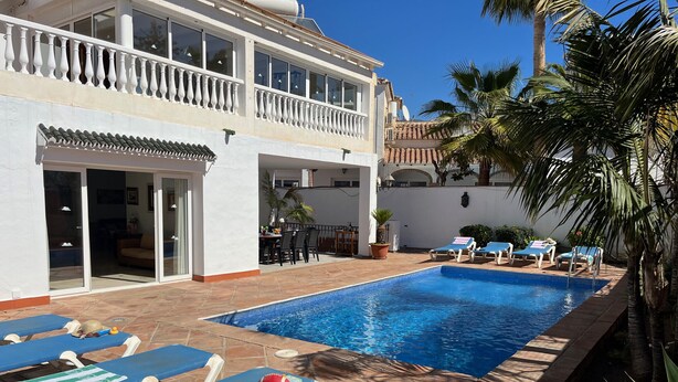 A swimming pool with lounge chairs, a dining area, and a white building with a balcony. - Nerja Paradise Rentals - Villa Almassora (Nerja)