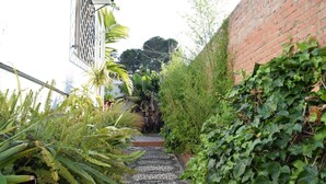A narrow pathway with a patterned rug, surrounded by lush greenery and a brick wall. - Nerja Paradise Rentals - Villa Almassora (Nerja)