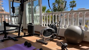 A gym with exercise equipment, including dumbbells, a stationary bike, and a large exercise ball. - Nerja Paradise Rentals - Villa Almassora (Nerja)