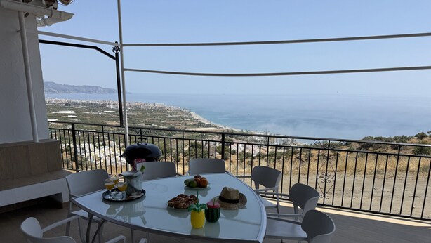Ein Balkon mit Tisch für zwei Personen, mit Blick auf die Küste.