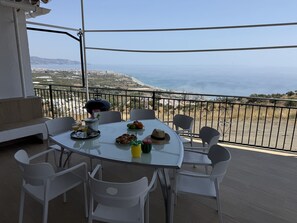 Un balcón con una mesa dispuesta para dos, con vistas a la costa.
