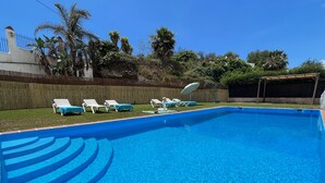Ein klares, blaues Schwimmbecken mit weißen Liegestühlen und einer Holzterrasse.