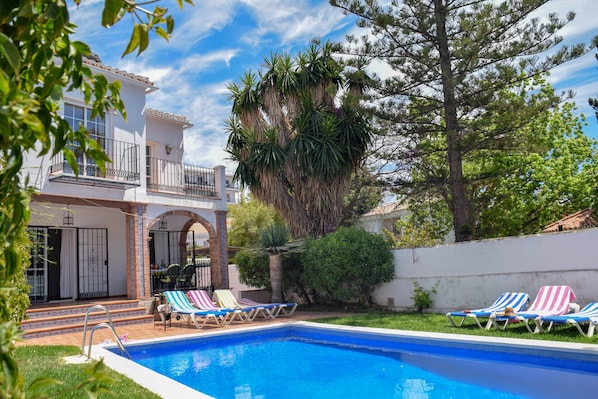 Relax by the pool surrounded by comfortable lounge chairs and lush greenery.