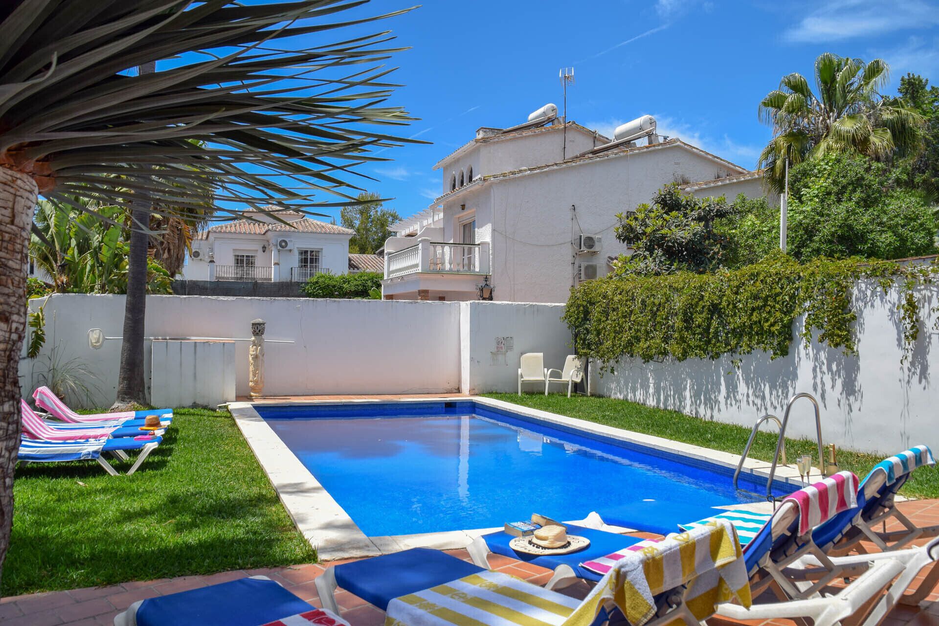 A swimming pool with lounge chairs and a tiled deck.
