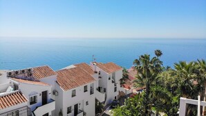 Un pueblo costero con edificios blancos y tejados de tejas rojas, con vistas al mar.