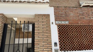 A building with a brick facade, a numbered sign, and a metal gate. - Nerja Paradise Rentals - Villa Jazmines (Nerja)