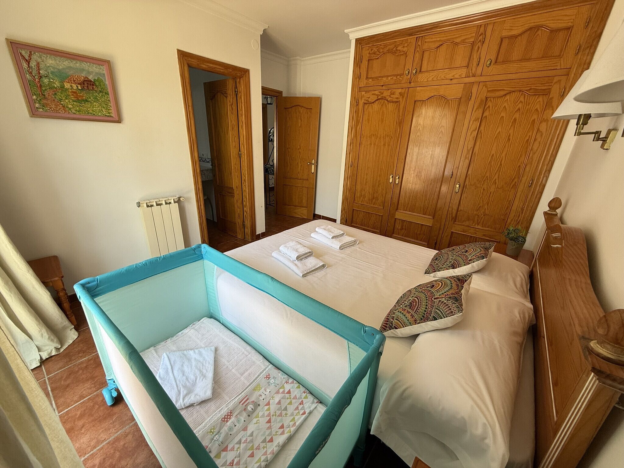 Ein Schlafzimmer mit einem Bett, einem Holzschrank und einem kleinen, blauen Kinderbett.