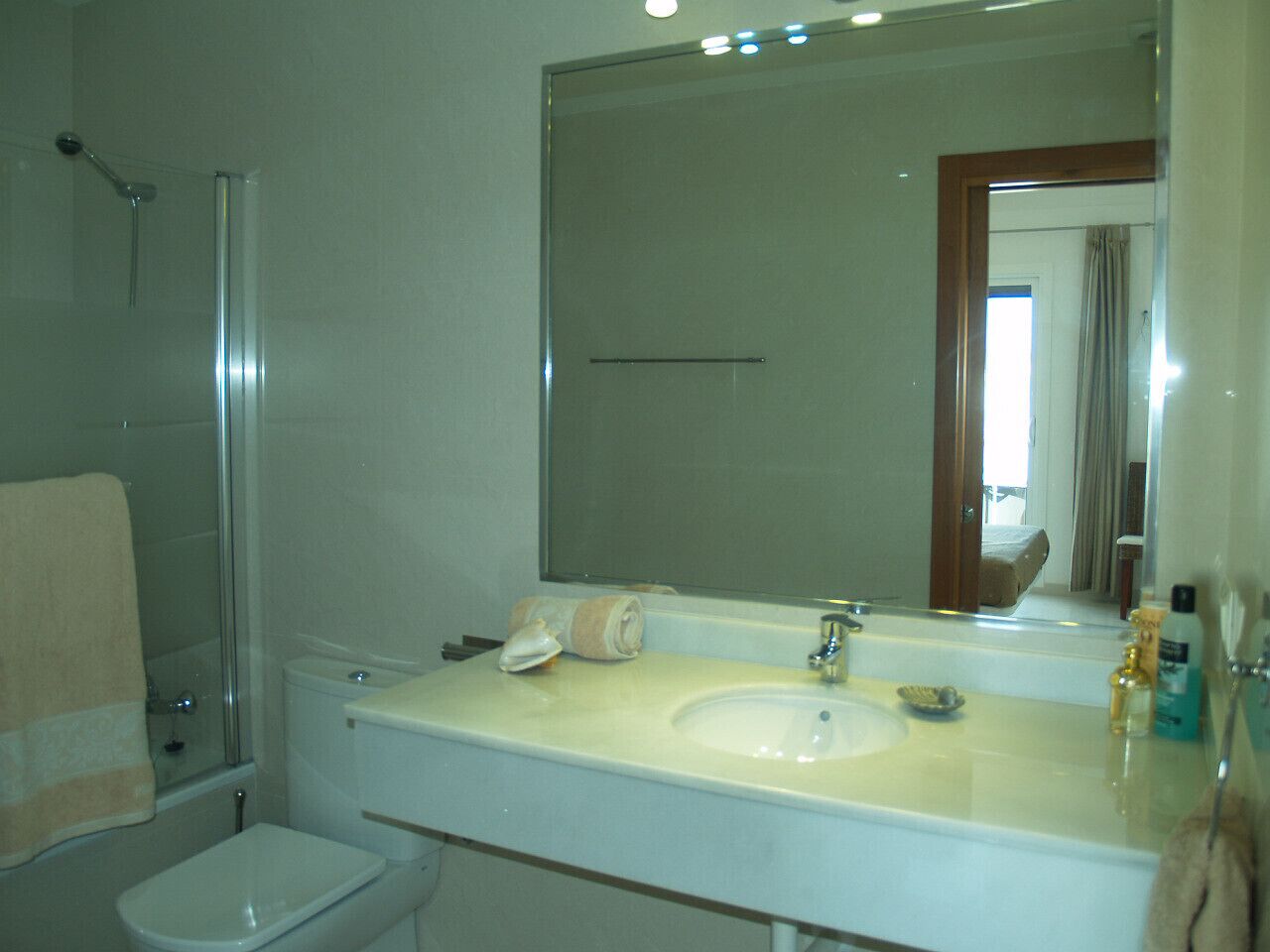 Une salle de bain équipée d’une douche, de toilettes, d’un lavabo et d’un grand miroir.