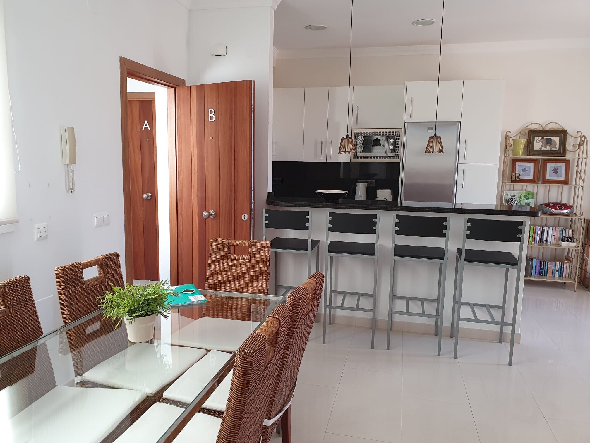 A modern kitchen with white cabinets, stainless steel appliances, and a central island with bar stools.