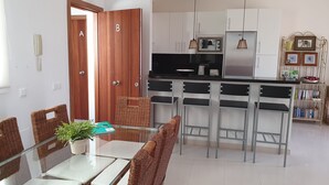 Una cocina moderna con armarios blancos, electrodomésticos de acero inoxidable y una isla central con taburetes de bar.