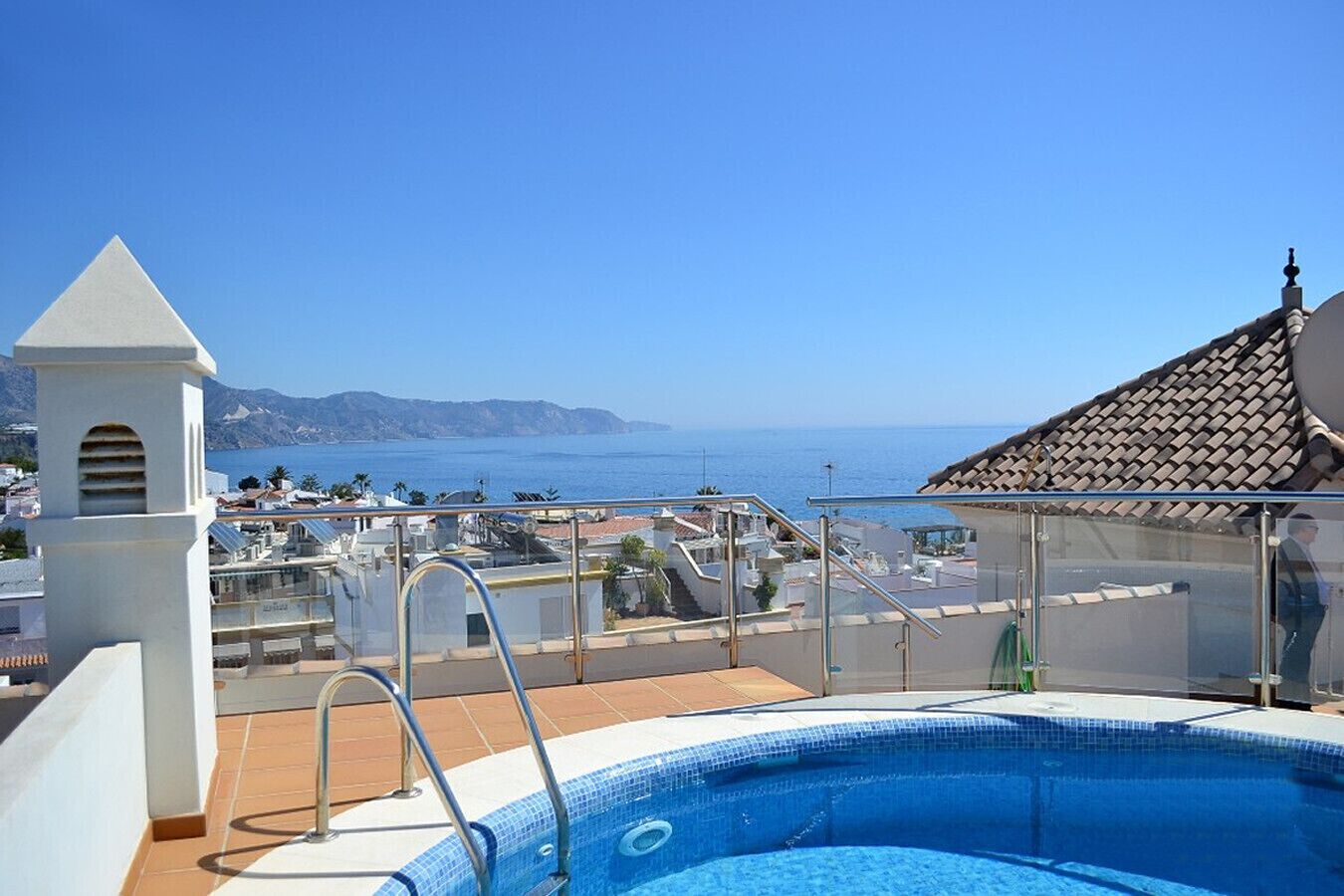 A rooftop pool with a clear view of the sea and mountains.
