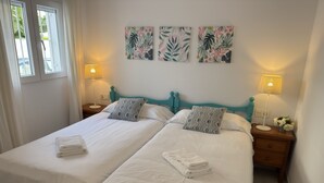 Une chambre avec un grand lit pour deux personnes, deux tables de chevet, chacune équipée d’une lampe et d’une petite plante.