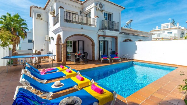 A poolside area with lounge chairs, a table, and a barbecue setup.