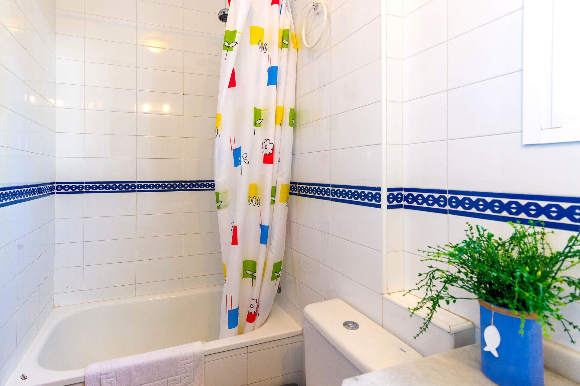 A bathroom with a bathtub, toilet, and shower curtain with colorful patterns.