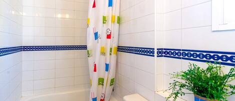 A bathroom with a bathtub, toilet, and shower curtain with colorful patterns.