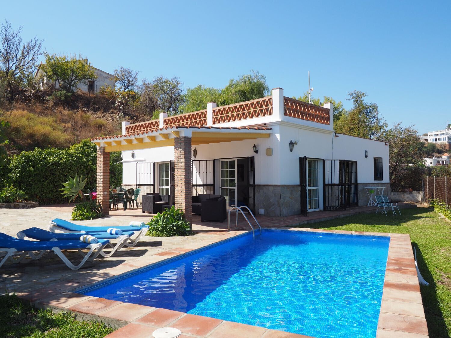 A modern house with a swimming pool, patio furniture, and a covered outdoor area.