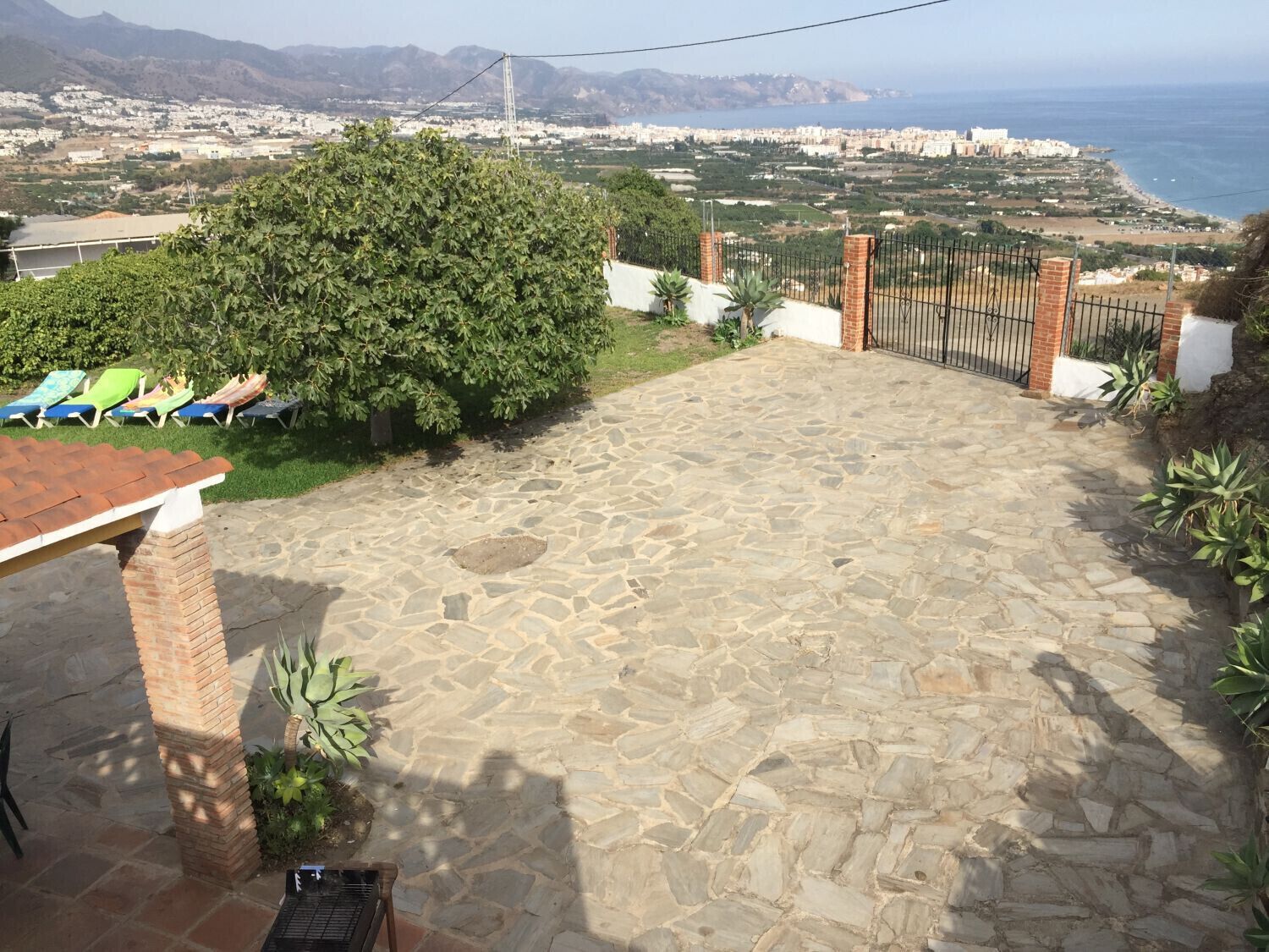 A stone patio with a view of a coastal cityscape, including mountains and a beach.