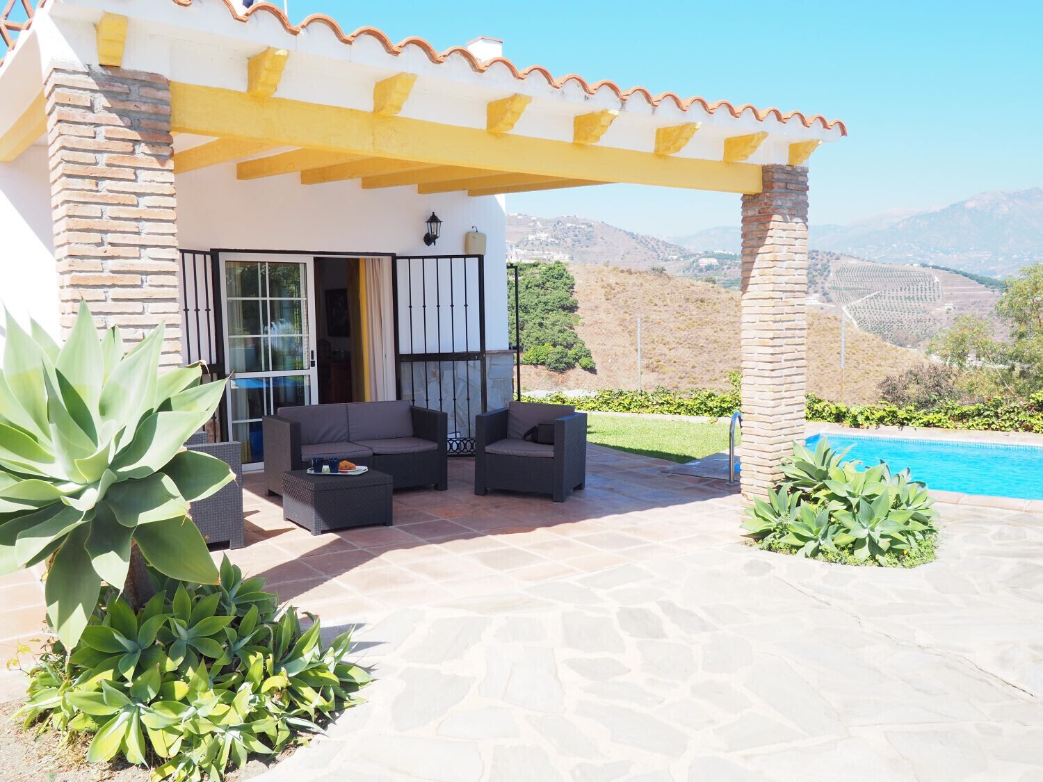 A patio with outdoor furniture, a pool, and a view of the mountains.
