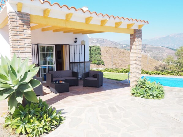 A patio with outdoor furniture, a pool, and a view of the mountains.