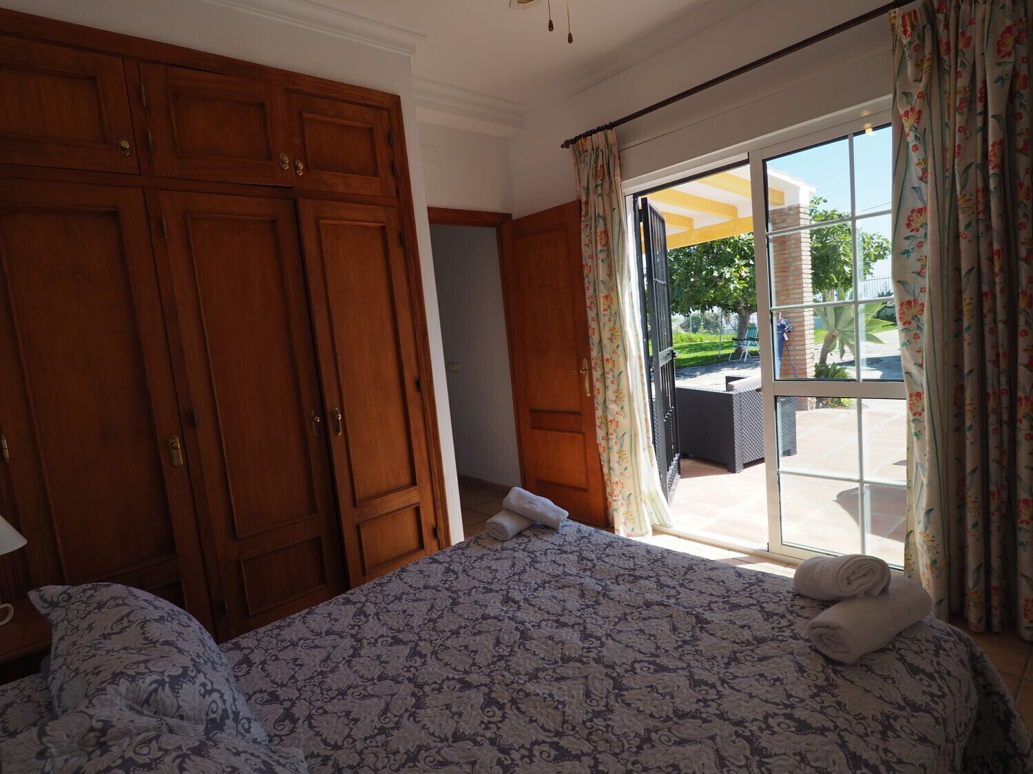 Camera d'albergo con un letto grande, un armadio in legno e una porta scorrevole in vetro che dà su uno spazio all'aperto.
