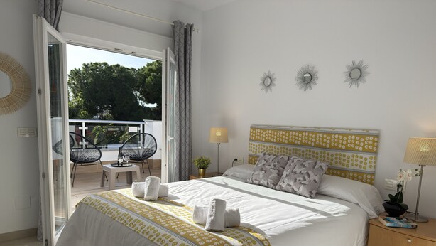 A hotel room with a bed, bedside tables, a lamp, and a view of the outdoor area. - Nerja Paradise Rentals - Villa Valeria (Nerja)