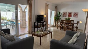 Una sala de estar con sofá, una mesa de centro, televisión y un comedor con sillas y mesa.