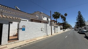 A street view with a building featuring a textured facade, a gated entrance, and a sign indicating 'Las Dalias.' - Nerja Paradise Rentals - Villa Las Dalias (Nerja)