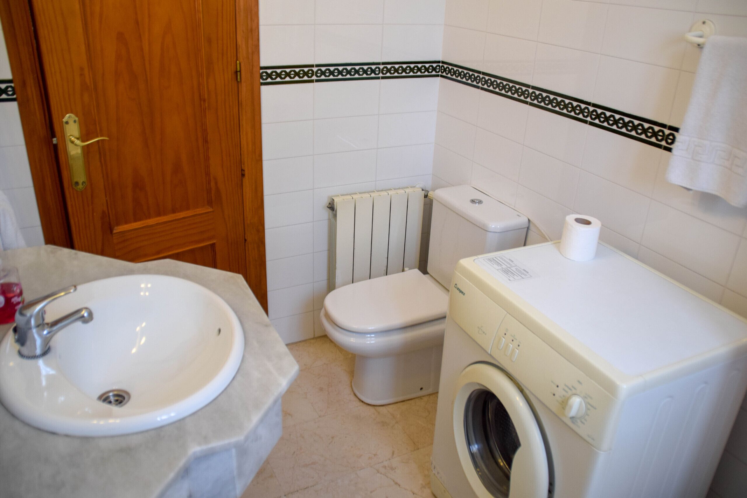 Un baño con lavamanos, inodoro y lavadora.