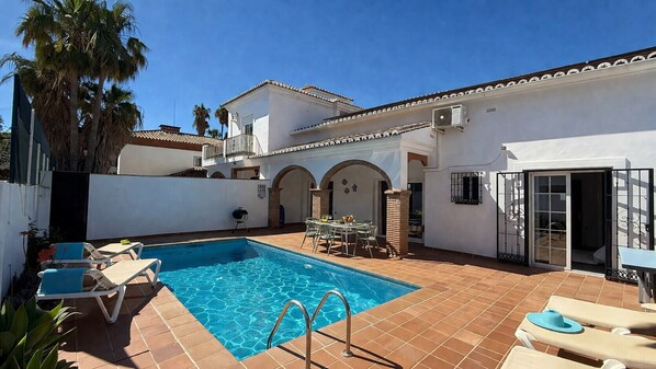 A swimming pool with lounge chairs, a table, and a covered patio area. - Nerja Paradise Rentals - Villa Las Dalias (Nerja)
