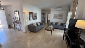 Una sala de estar con un sofá, una mesa de centro y un mueble para televisor.