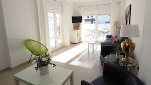 Una sala moderna con una mesa de centro de vidrio, un sillón verde, un sofá y una lámpara.