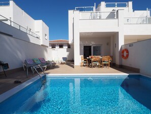 A swimming pool with lounge chairs and a table, surrounded by white buildings. - Nerja Paradise Rentals - Villa Bonilla (Nerja)