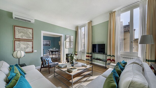 Sala de estar con sofá, mesa de centro, televisor y comedor.