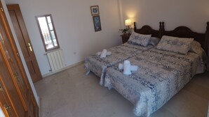A bedroom with a large bed, a wooden wardrobe, a radiator, a window, and a wall-mounted air conditioner. - Nerja Paradise Rentals - Villa Victoria (Nerja)