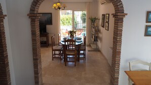 A dining area with a brick archway, a chandelier, and a view of the outdoors. - Nerja Paradise Rentals - Villa Victoria (Nerja)