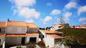 A residential area with terracotta-tiled roofs, white walls, and a clear blue sky with scattered clouds. - Guilhim Guest House (Nazaré)