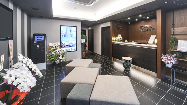 A hotel reception area with a reception desk, a digital display, and seating. - Hotel Livemax Asakusa Ekimae (Tokyo)
