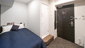 A hotel room with a bed, a door, a small step leading to the door, and a wall-mounted control panel. - Hotel Livemax Asakusa Ekimae (Tokyo)