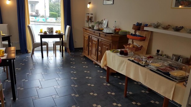Ein Essbereich mit einem Buffet, Stühlen, einer Uhr und einem Fenster mit Vorhängen.