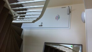 Eine Treppe mit weißen Spindeln, eine Tür mit einem Hotel-Logo und ein Spiegel an der Wand.