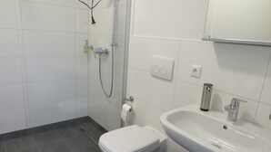 Une salle de bain avec des toilettes, un lavabo et une douche.