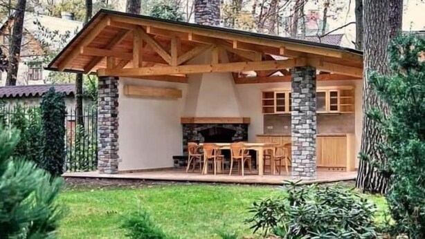 A wooden cabin with stone pillars, a fireplace, and a dining area with chairs. - Pension Karolingerweg (Lauterhofen)