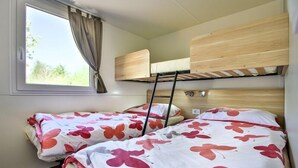 A compact room with two bunk beds, a window with curtains, and a view of greenery outside. - Kamp Slapic Mobile Homes (Duga Resa)