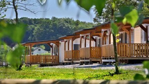 A row of wooden cabins with balconies, set against a backdrop of dense forest. - Kamp Slapic Mobile Homes (Duga Resa)