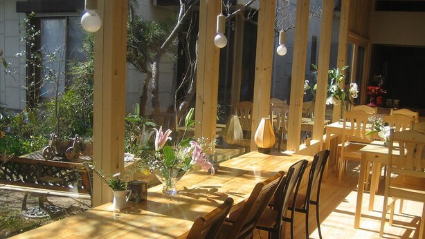 A wooden dining area with tables and chairs, large windows, and hanging light fixtures. - Yamashiroya (Nara)