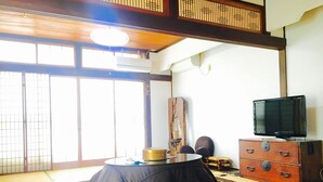 A traditional tatami mat room with a tatami mat table, a television on a wooden cabinet, and a sliding door with a view of the outside. - Yamashiroya (Nara)