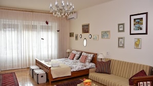 A bedroom with a bed, a sofa, a chandelier, and artwork on the walls. - Apartments Oldtimer (Zagreb)