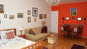 A furnished room with a bed, a sofa, a dining table with chairs, and a chandelier. - Apartments Oldtimer (Zagreb)
