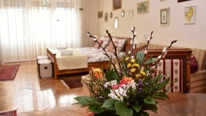 A cozy living room with a wooden coffee table, a bed with a white comforter, and a wall adorned with framed pictures. - Apartments Oldtimer (Zagreb)
